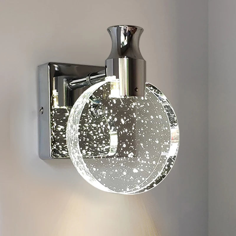 Chrome wall sconce with a round, glass-like shade on a neutral background