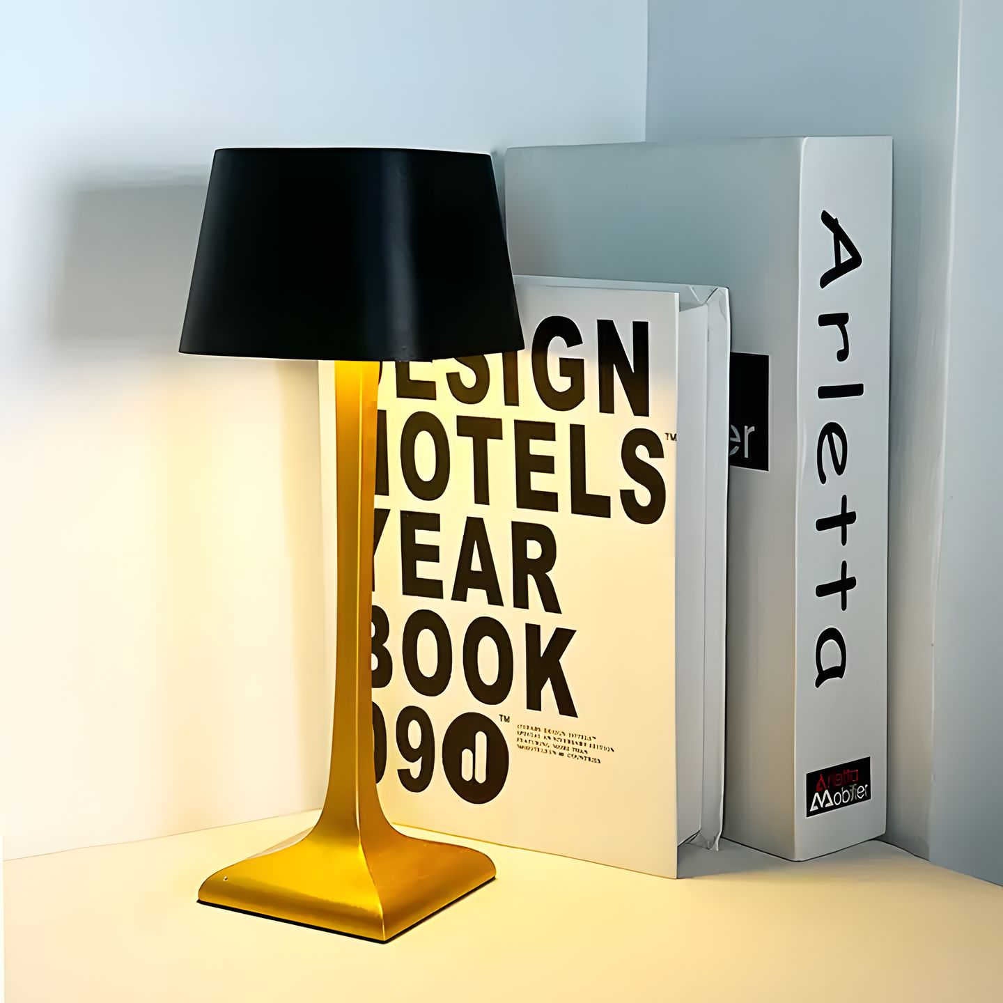 Black and gold lamp on a surface with books in the background