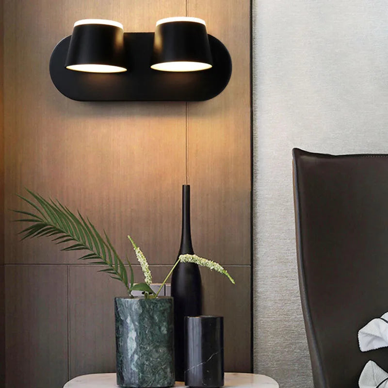 Modern wall light fixture with decorative vases and a plant in a room setting.