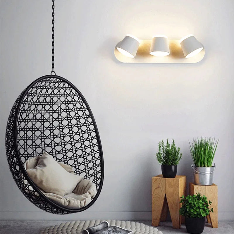 Hanging egg chair in a modern room with plants and wall light fixture.