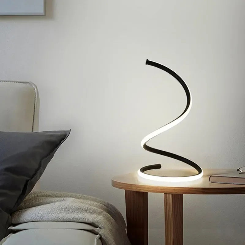 Modern lamp with curved design on a wooden side table in a room setting.