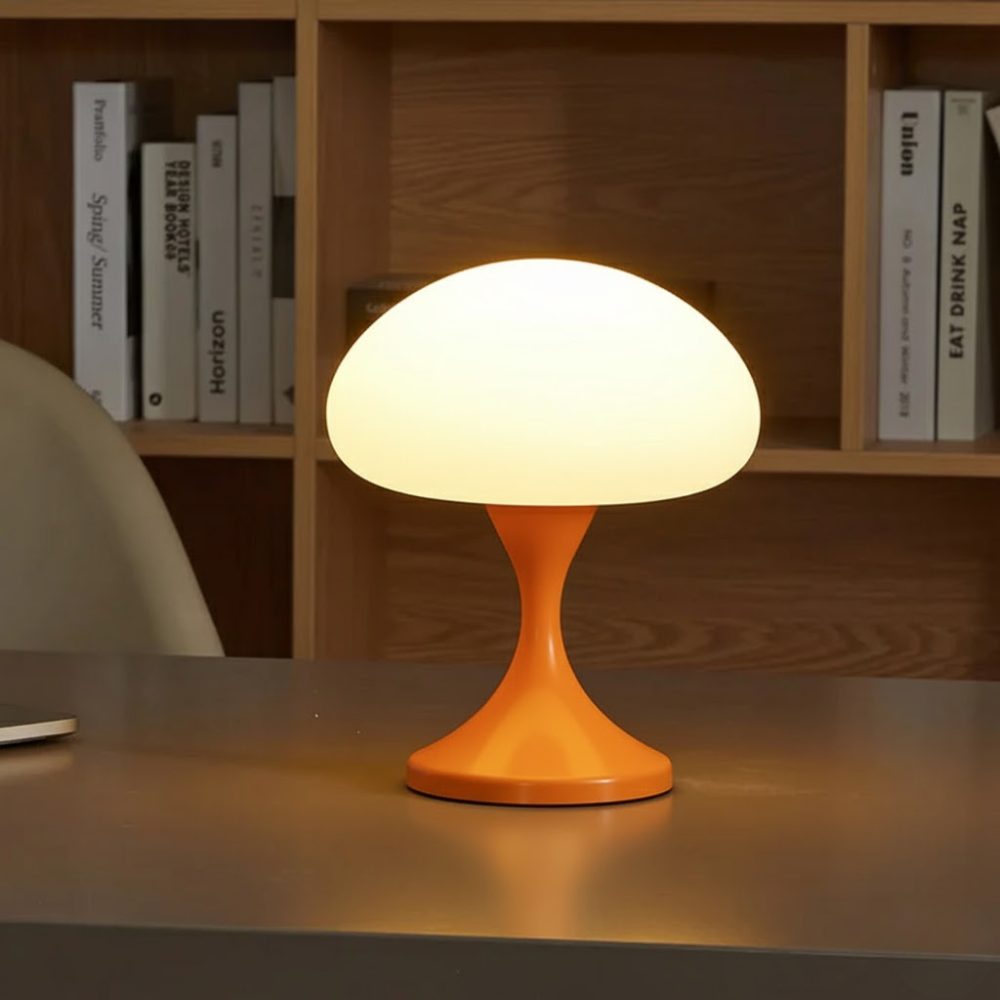 Orange mushroom-shaped lamp on a desk with books in the background