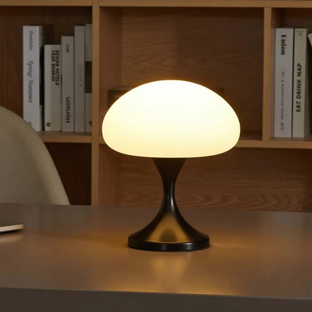 Mushroom-shaped table lamp on a desk with books in the background