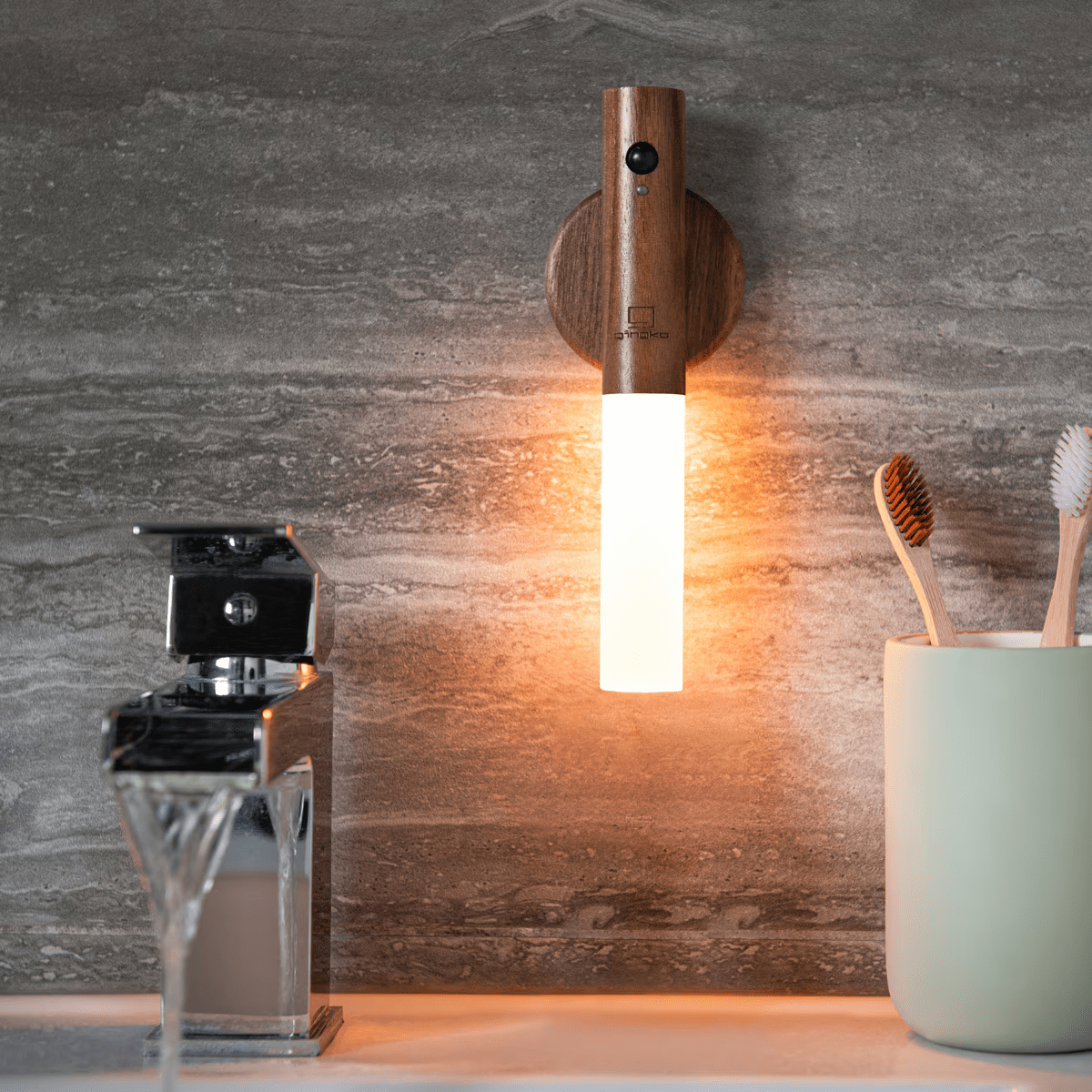 Wooden wall-mounted lamp on a bathroom wall with a razor and toothbrush holder below.