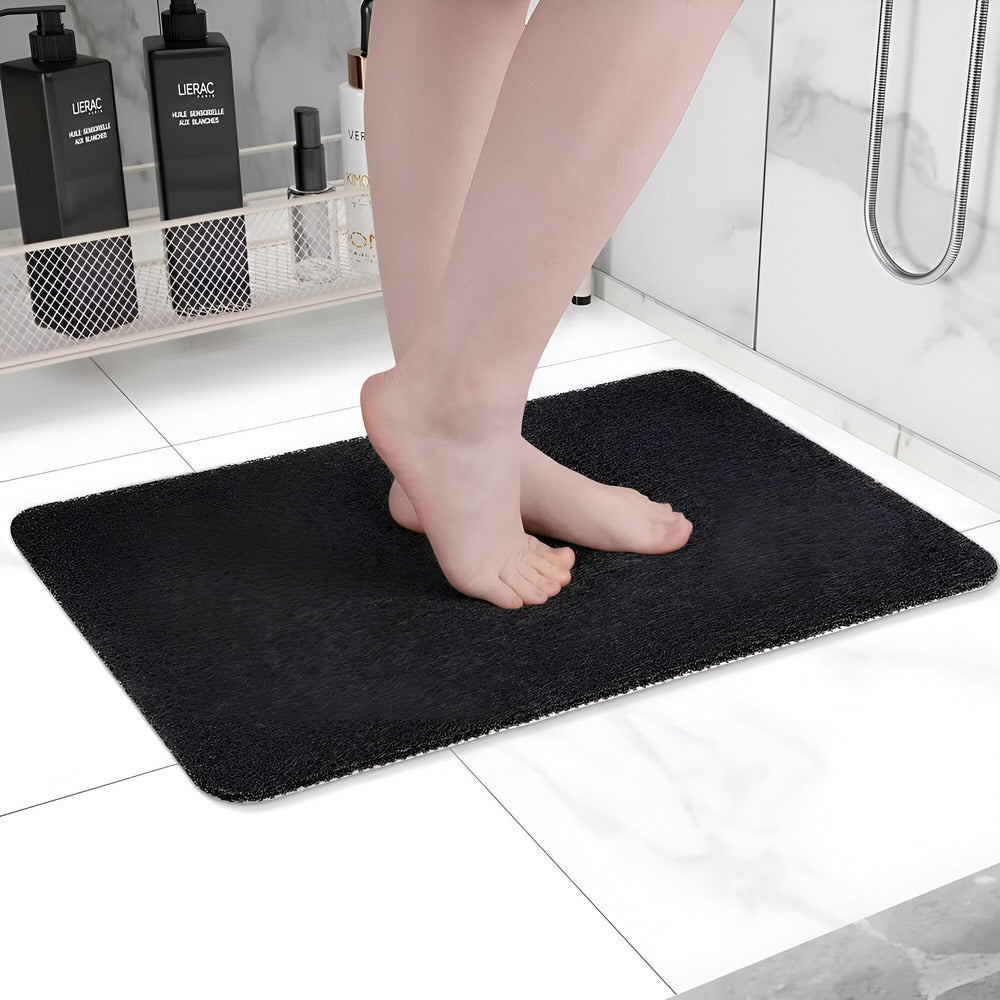 Person standing on a black bath mat in a bathroom setting.