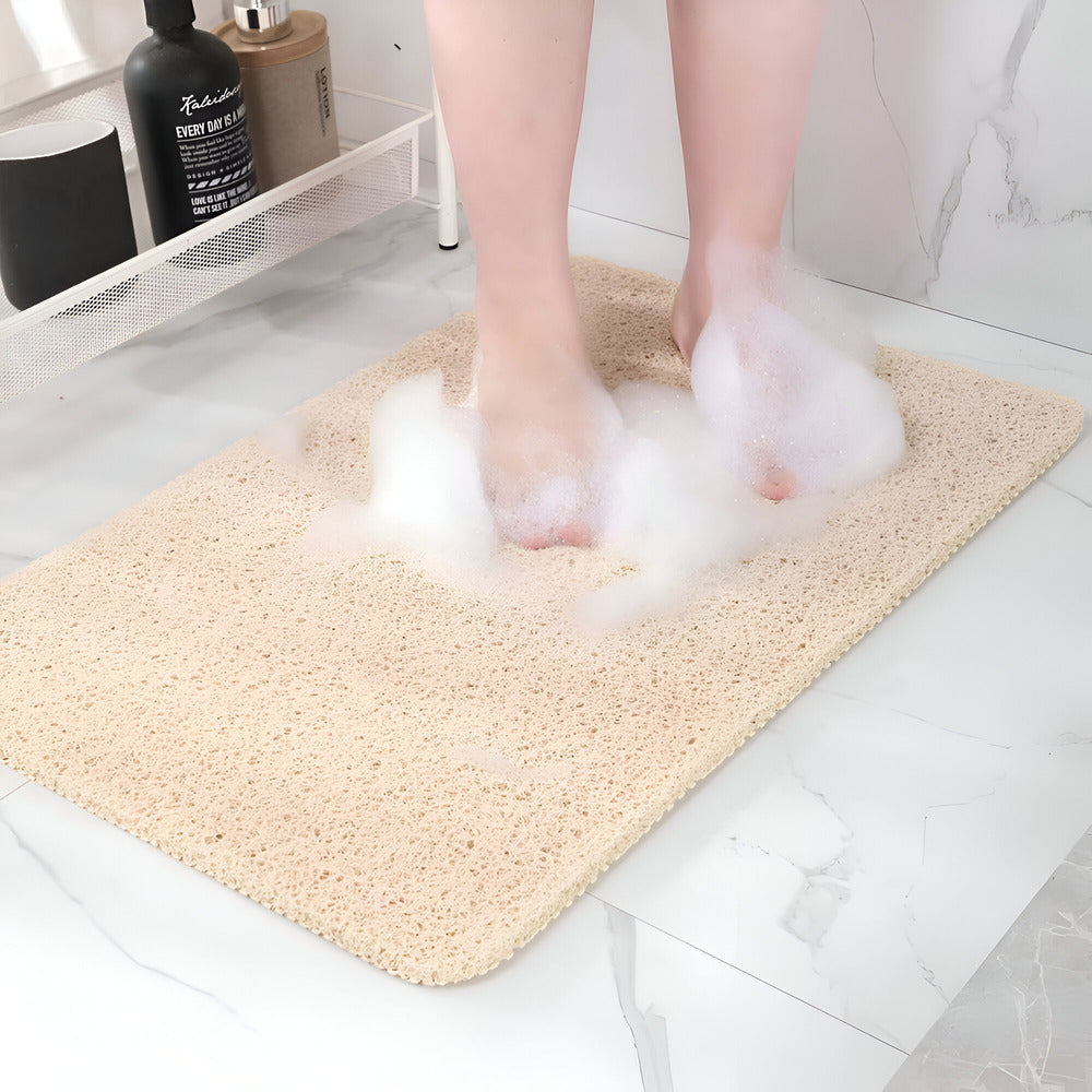 Person stepping onto a textured bath mat with soapy water splashes in a bathroom setting.