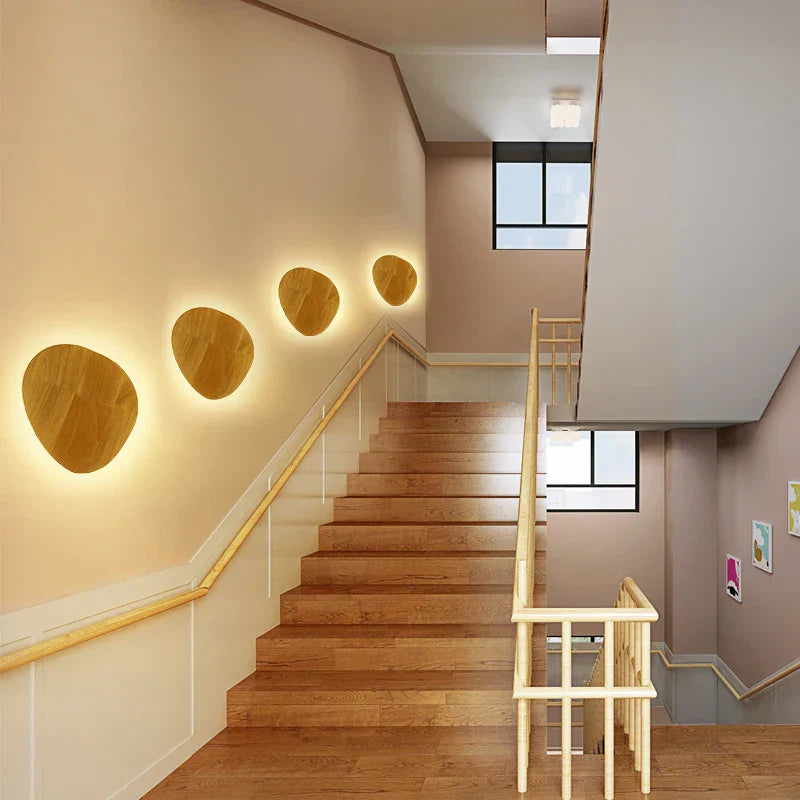 Staircase with wooden steps and wall-mounted round lights in a modern interior setting.