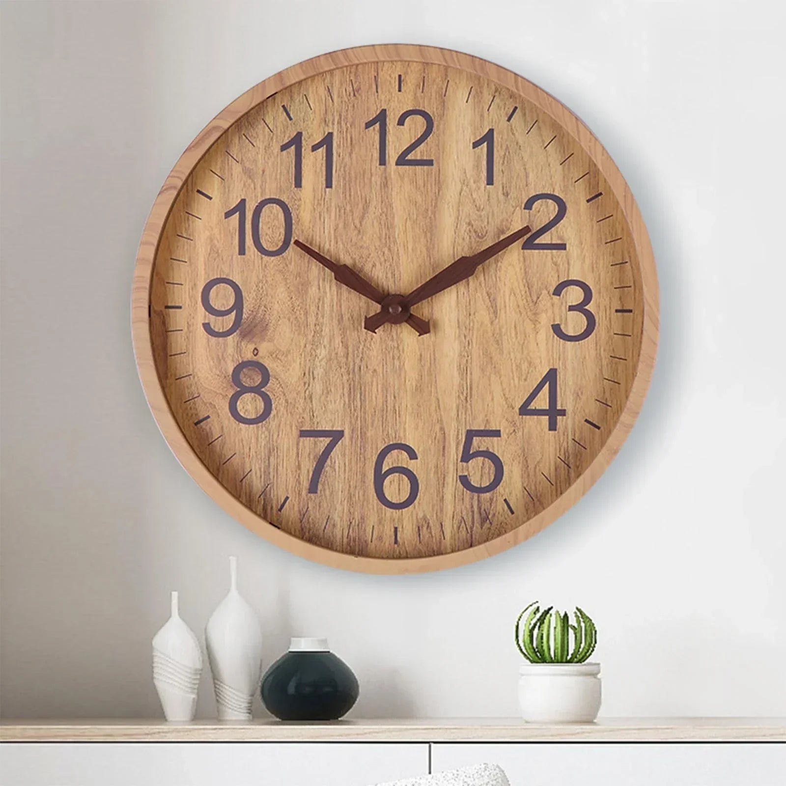 Wooden wall clock on a white wall with decorative items below.