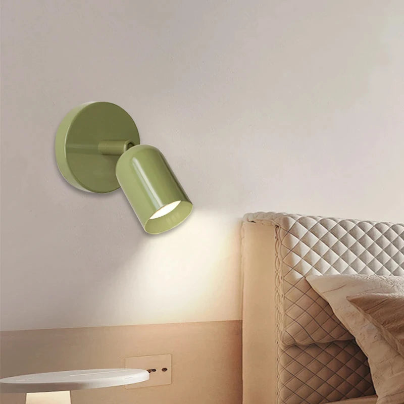 Green wall-mounted lamp on a neutral wall next to a bed