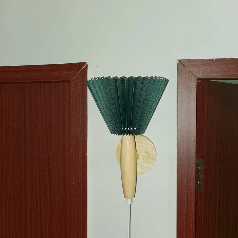 Green lamp with wooden handle against a white wall