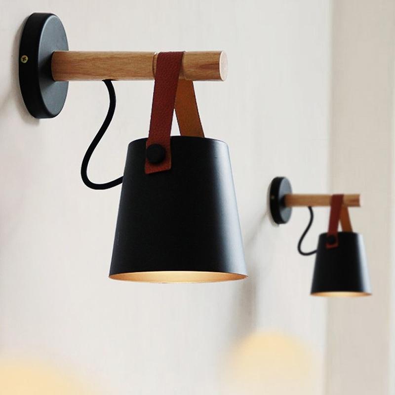 Wall-mounted lamp with black shade and wooden arm on a light background