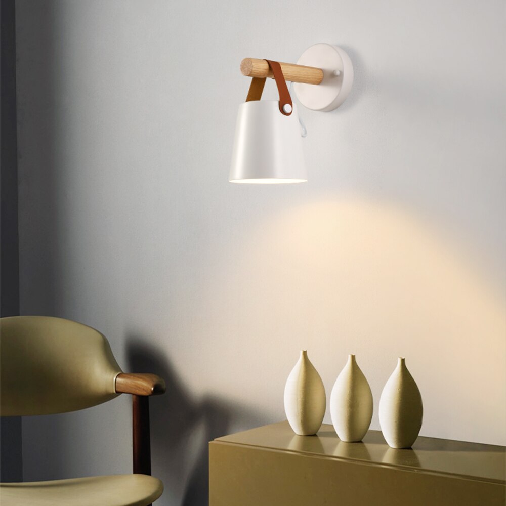 Modern wall lamp with wooden accents on a gray wall, next to a chair and decorative vases.