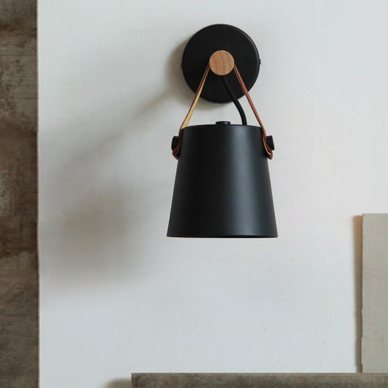Black wall sconce with leather strap on a white wall