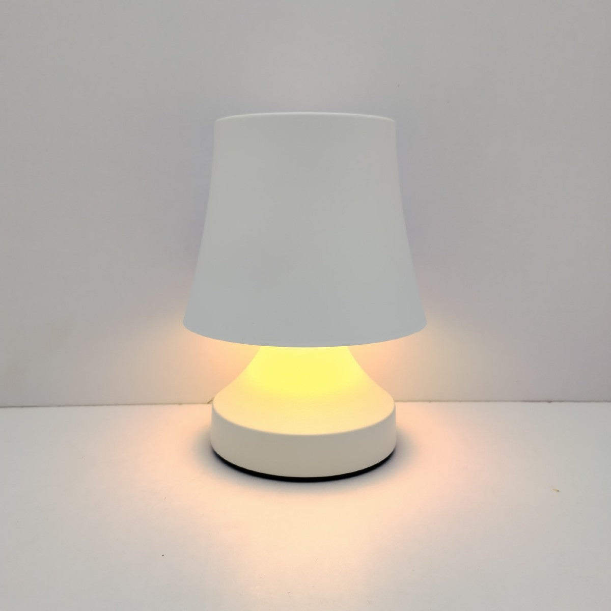 Small table lamp with a white shade and base on a light gray background