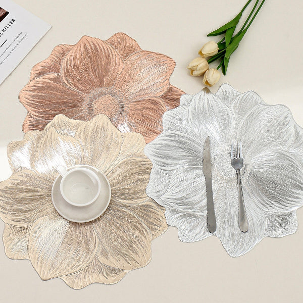 Floral-patterned placemats on a table with cutlery and a cup.