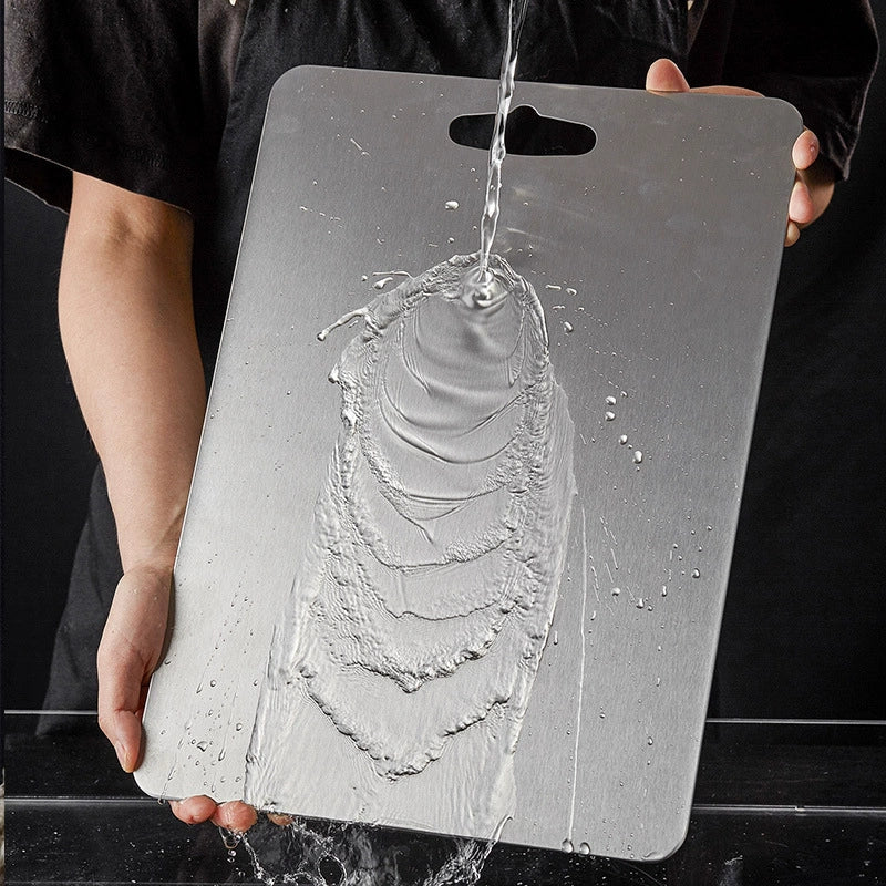 Person holding a metallic cutting board with water being poured onto it against a black background