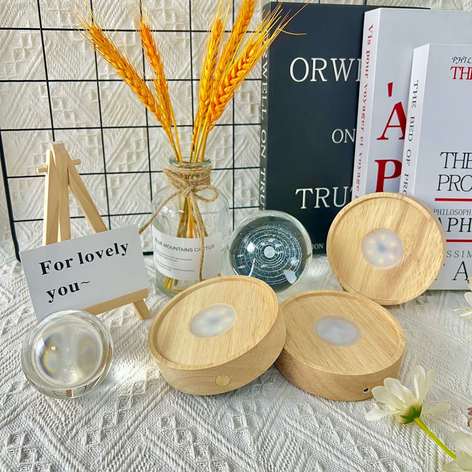 Wooden diffusers with a vase of wheat, books, and a card on a textured surface.