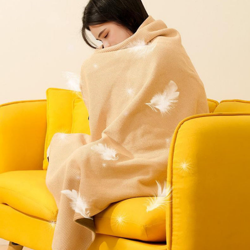Person wrapped in a beige blanket with white floral patterns on a yellow couch.