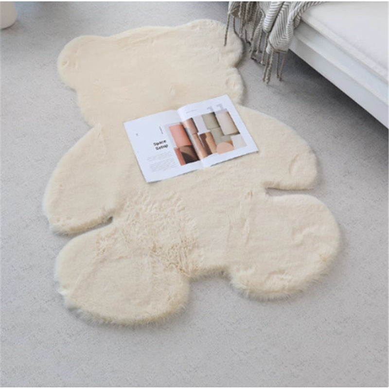 Beige teddy bear-shaped rug on a light gray floor with a magazine on top.