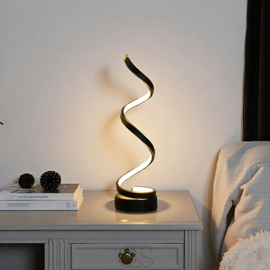 Modern table lamp with wavy design on a nightstand next to books and decorative items.