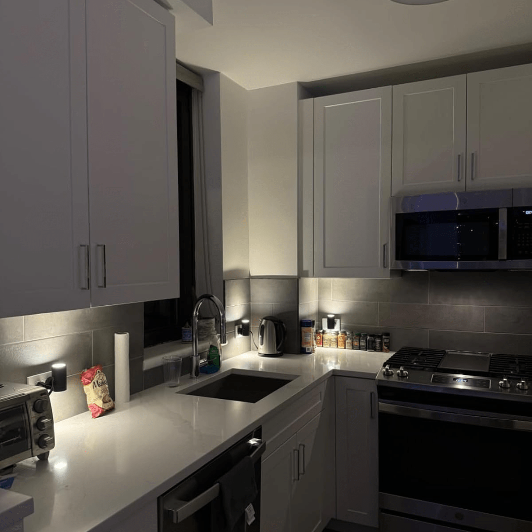 Modern kitchen with white cabinets, black appliances, and a tiled backsplash.