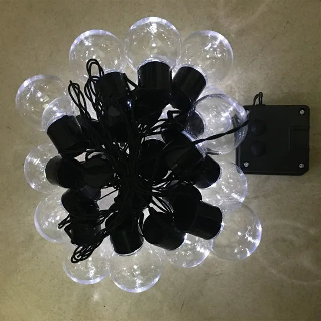String of clear light bulbs with black connectors on a beige surface