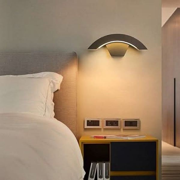 Modern wall lamp above a bedside table in a bedroom setting