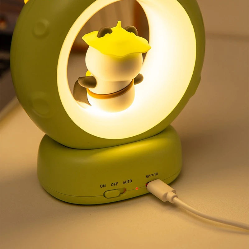 Green night light with a cartoon character inside, plugged in on a beige surface.