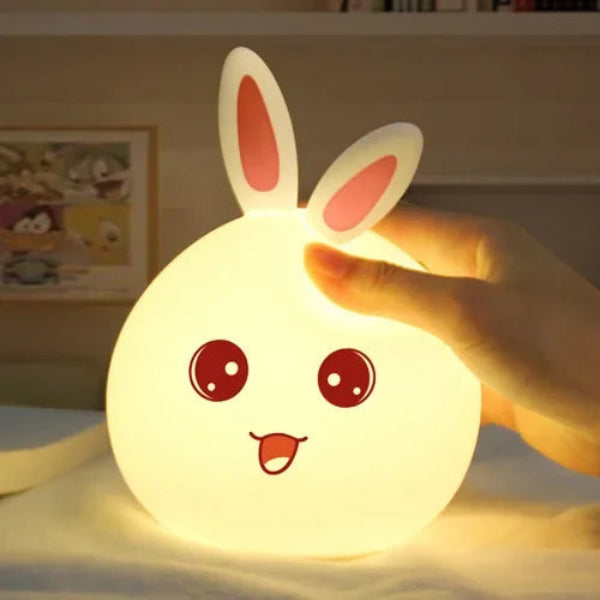 Glowing rabbit-shaped night light held by a hand with a blurred background