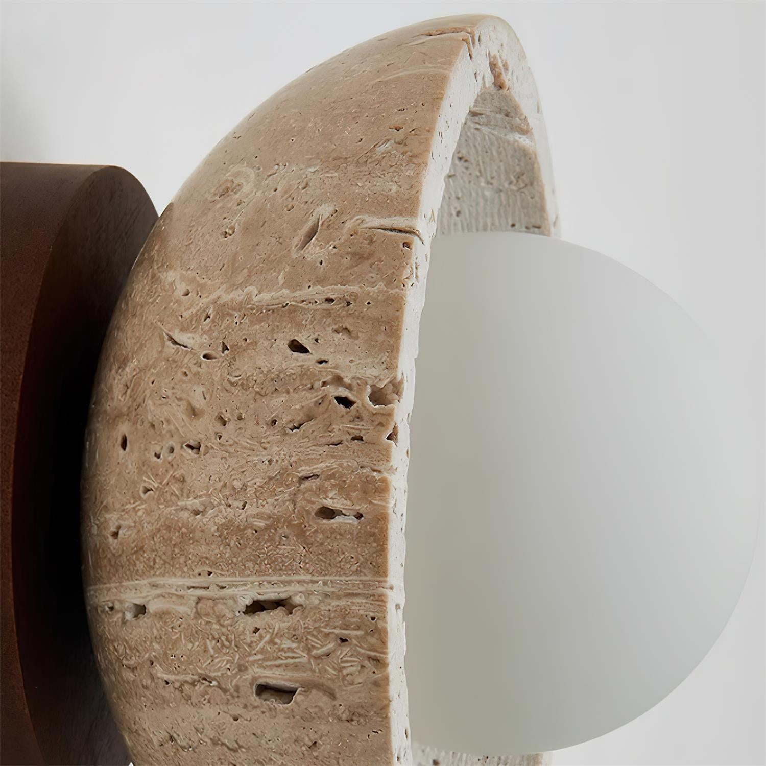 Close-up of a textured stone wall with a white light fixture.