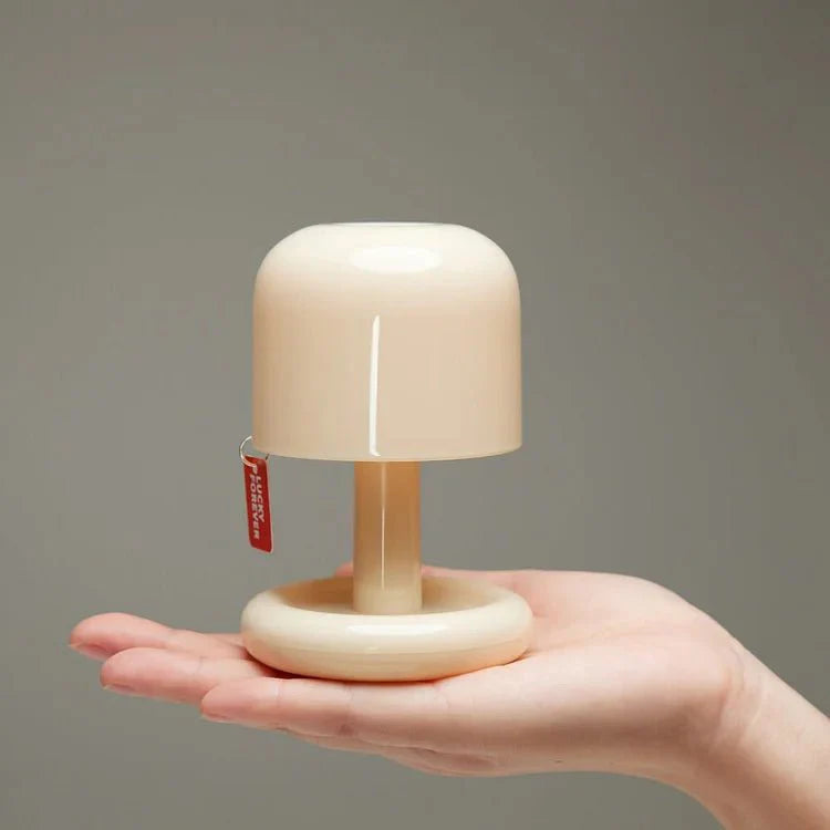 Small beige lamp held in a hand against a gray background