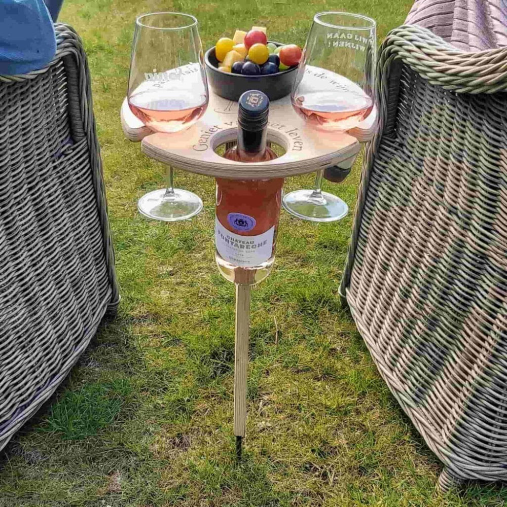 Portable outdoor table with wine bottle and glasses on a grassy area