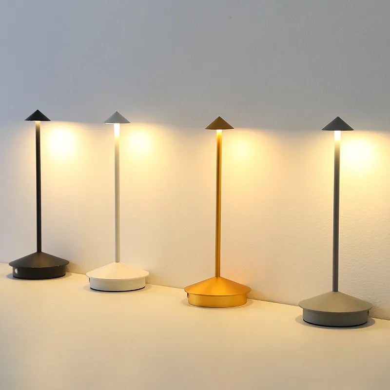 Four table lamps with different base colors on a light gray background
