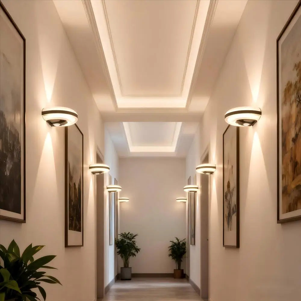 Modern hallway with decorative lighting, framed artwork, and potted plants.