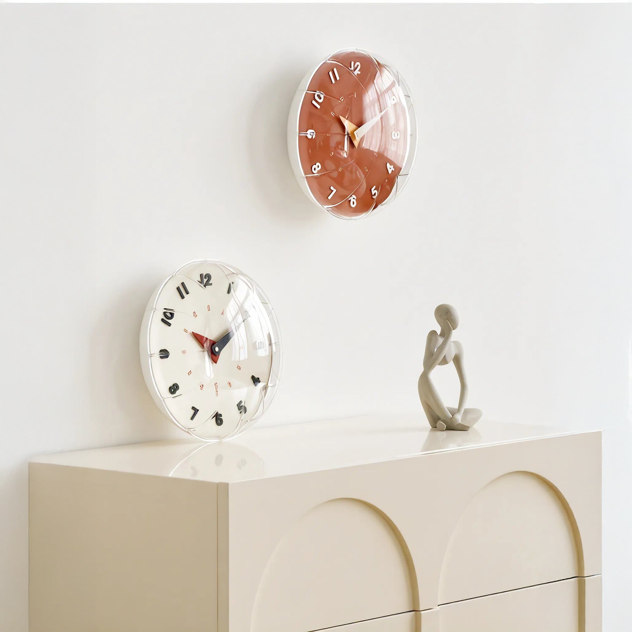 Two wall clocks on a white surface with a minimal background