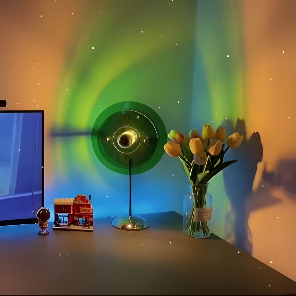 Desk with a computer monitor, decorative items, and a vase of tulips under a green and orange light projection.