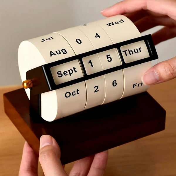 Perpetual calendar being adjusted by a hand on a wooden base.