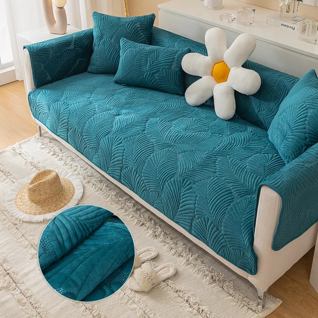 Teal textured sofa cover on a white sofa with decorative pillows and a flower-shaped pillow.