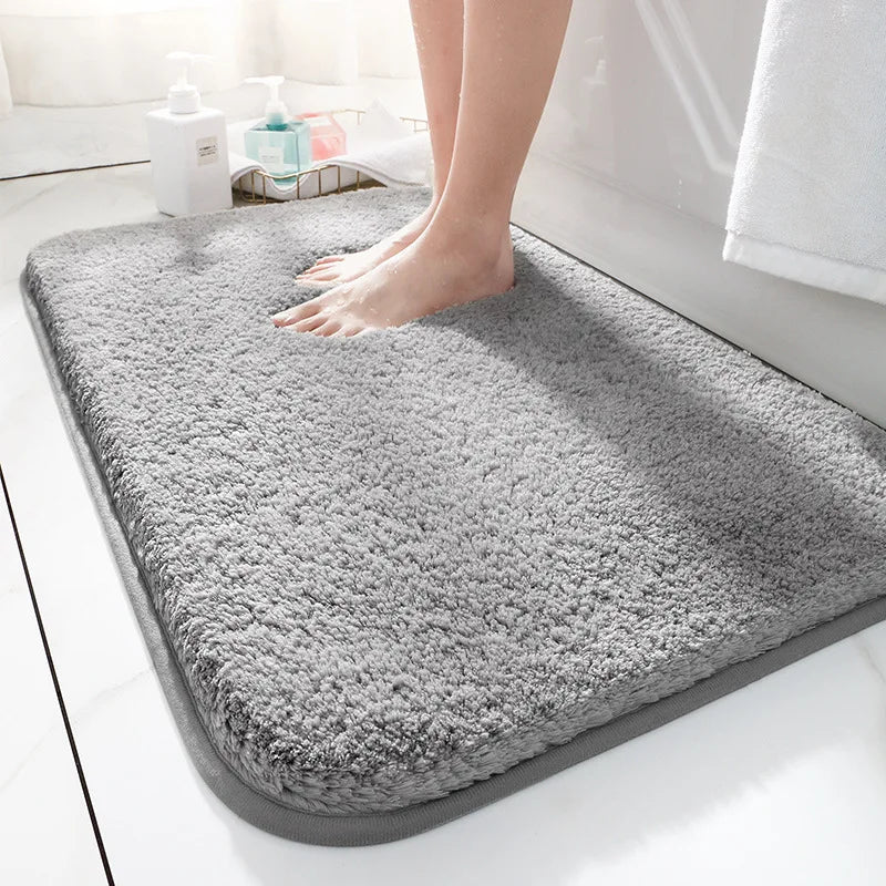 Gray bath mat on a bathroom floor with a person stepping onto it.
