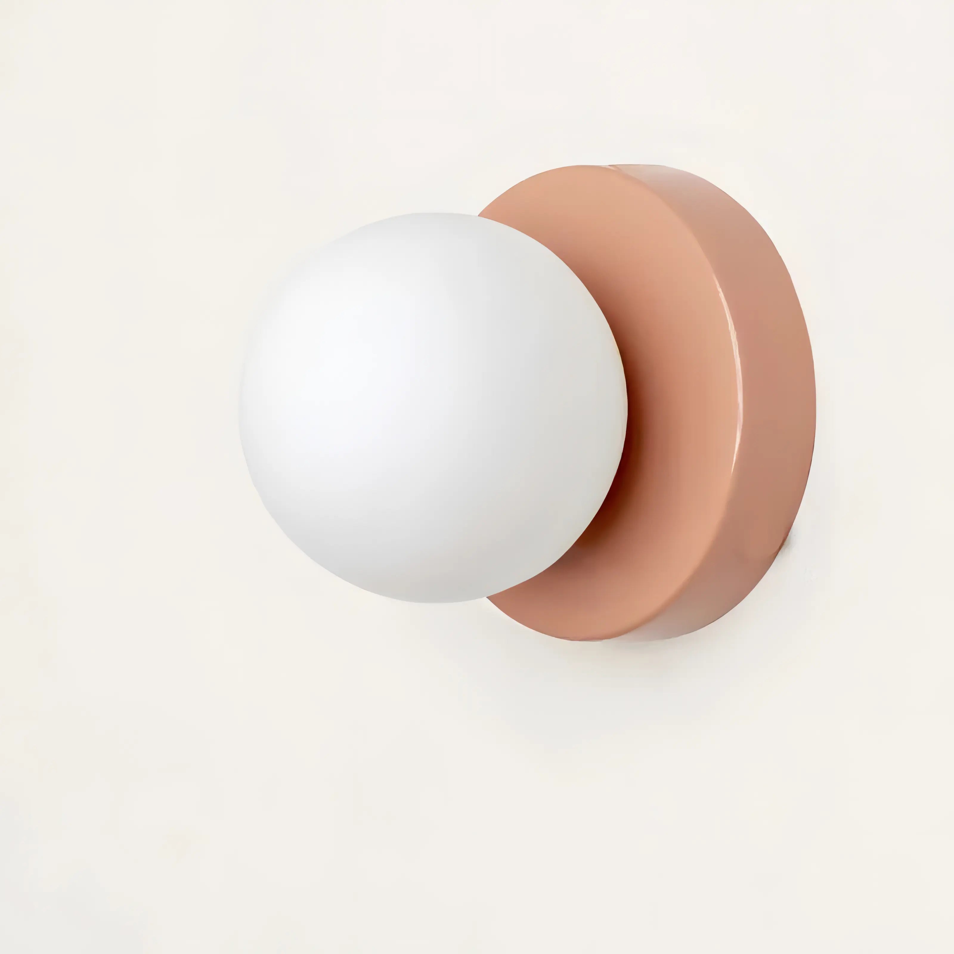 Wall sconce with white globe light and rose gold finish on a white background