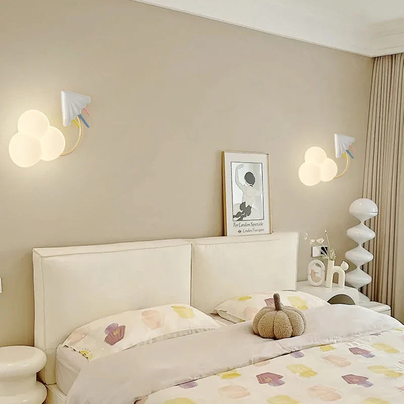Neatly made bed in a bedroom with decorative pillows and a pumpkin, featuring wall lights and a framed picture.
