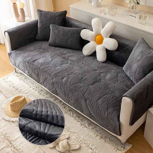 Gray textured sofa cover on a sofa with decorative pillows and a large flower-shaped pillow.