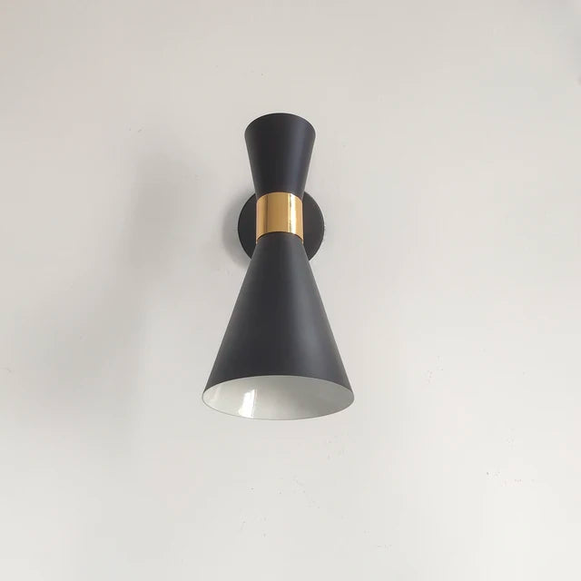 Black wall light fixture with gold accent on a white background