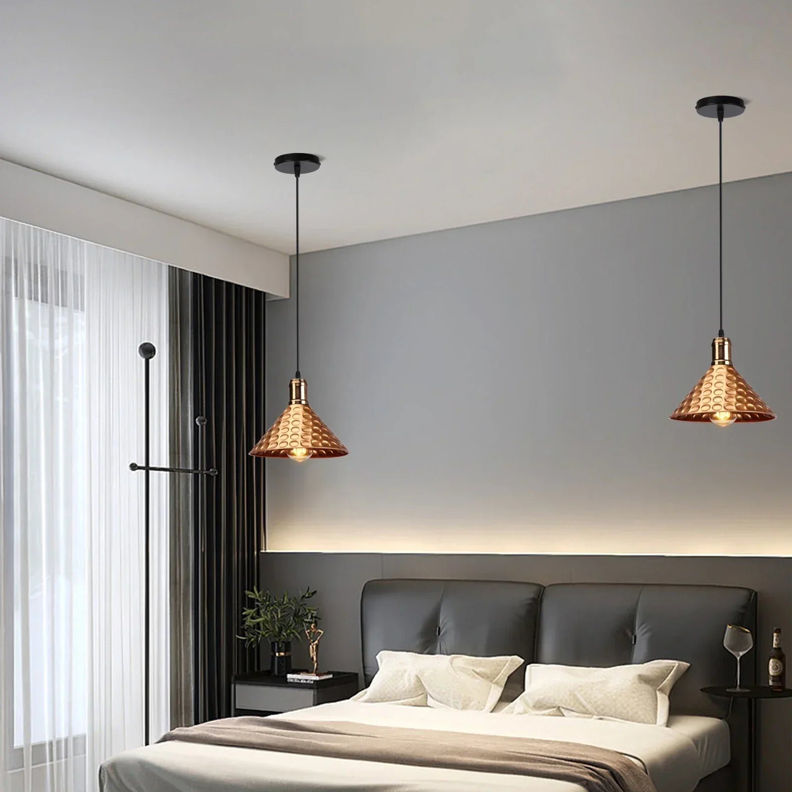 Pair of gold textured pendant lights hanging above a modern bed in a stylish bedroom.