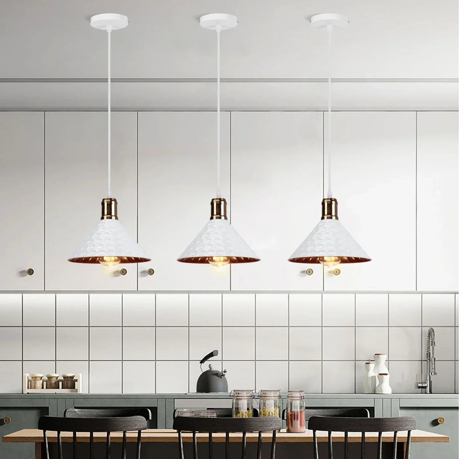 Set of three white and gold pendant lights hanging above a modern kitchen dining area.