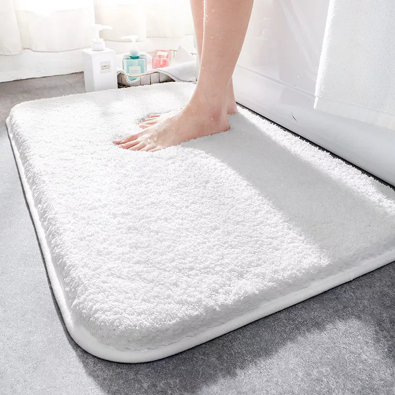 White bath mat on a bathroom floor with a person stepping onto it.