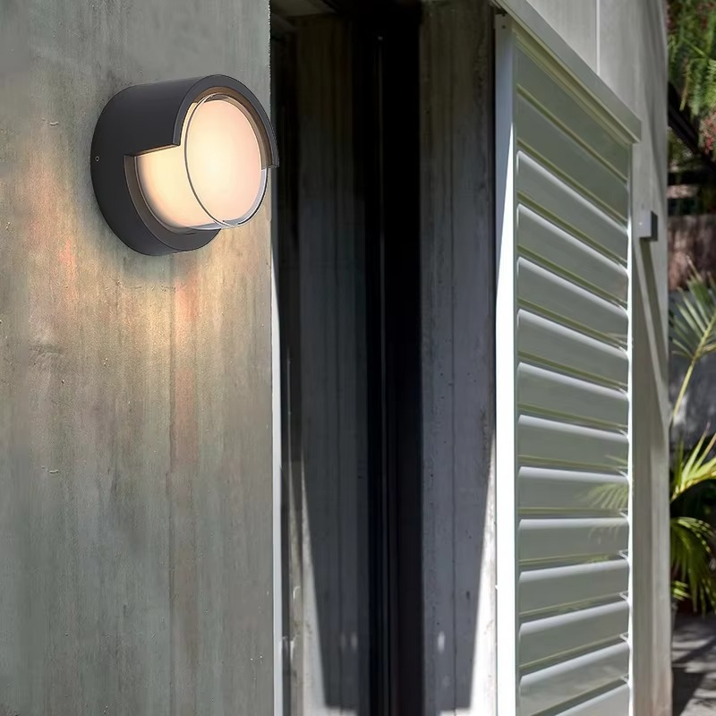 Outdoor wall light fixture on a concrete wall with a metal shutter in the background.