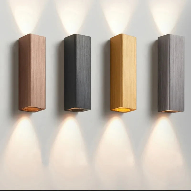 Four wall-mounted lights in different colors on a light gray background