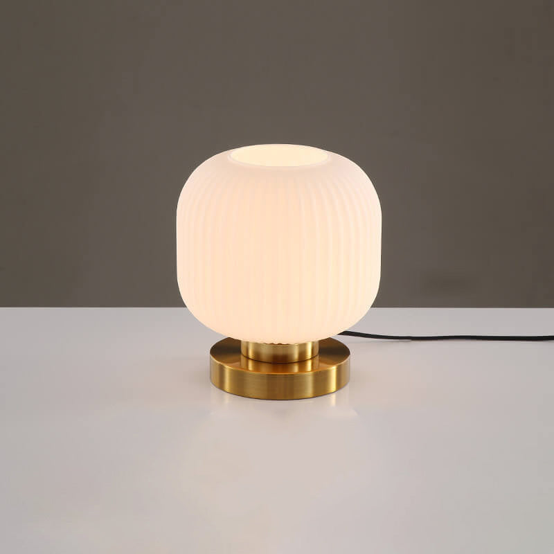Table lamp with white textured shade and gold base on a neutral background