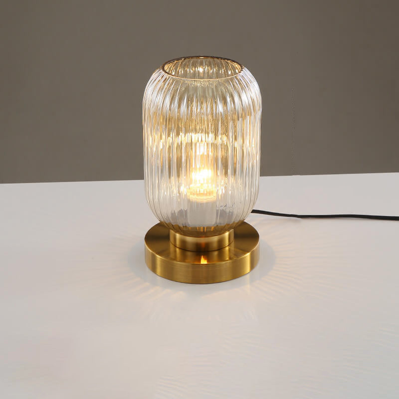 Table lamp with ribbed glass shade and gold base on a white surface.
